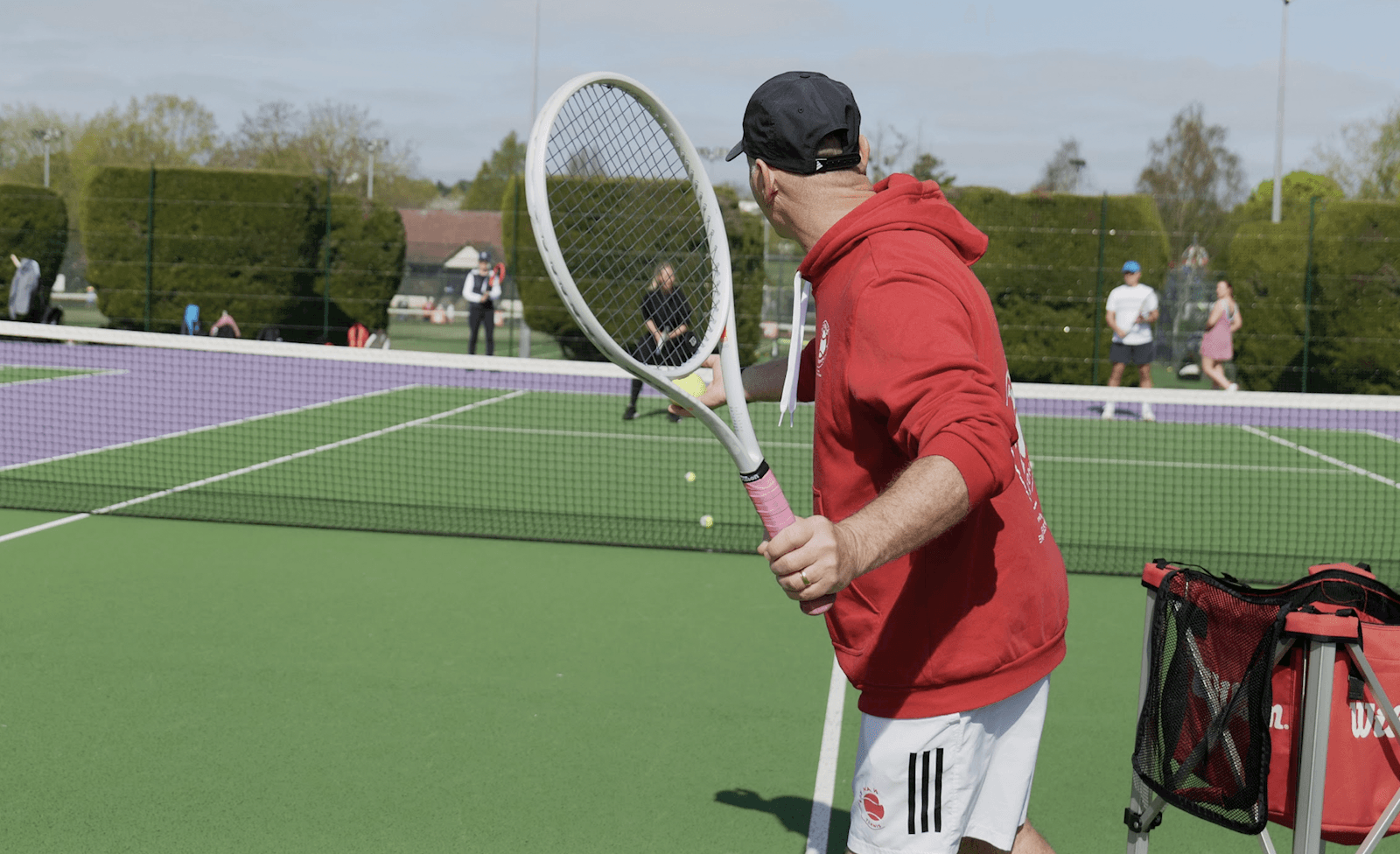 A player at the net at Dundonald Recreation Ground, racket raised, courts busy behind